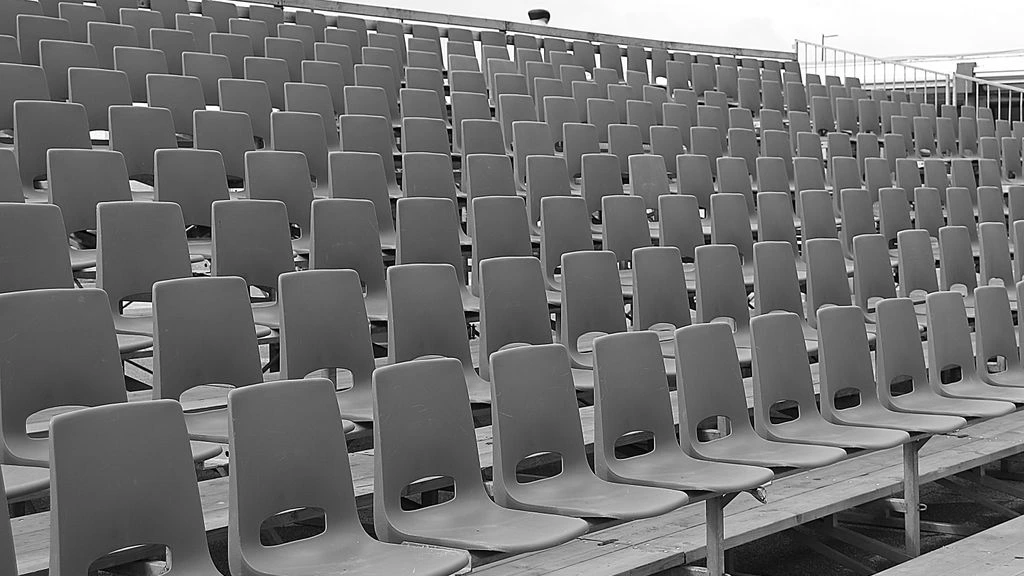 Empty leather director's chair on a dimly lit soundstage, photographed in black and white with a warm sepia wash.